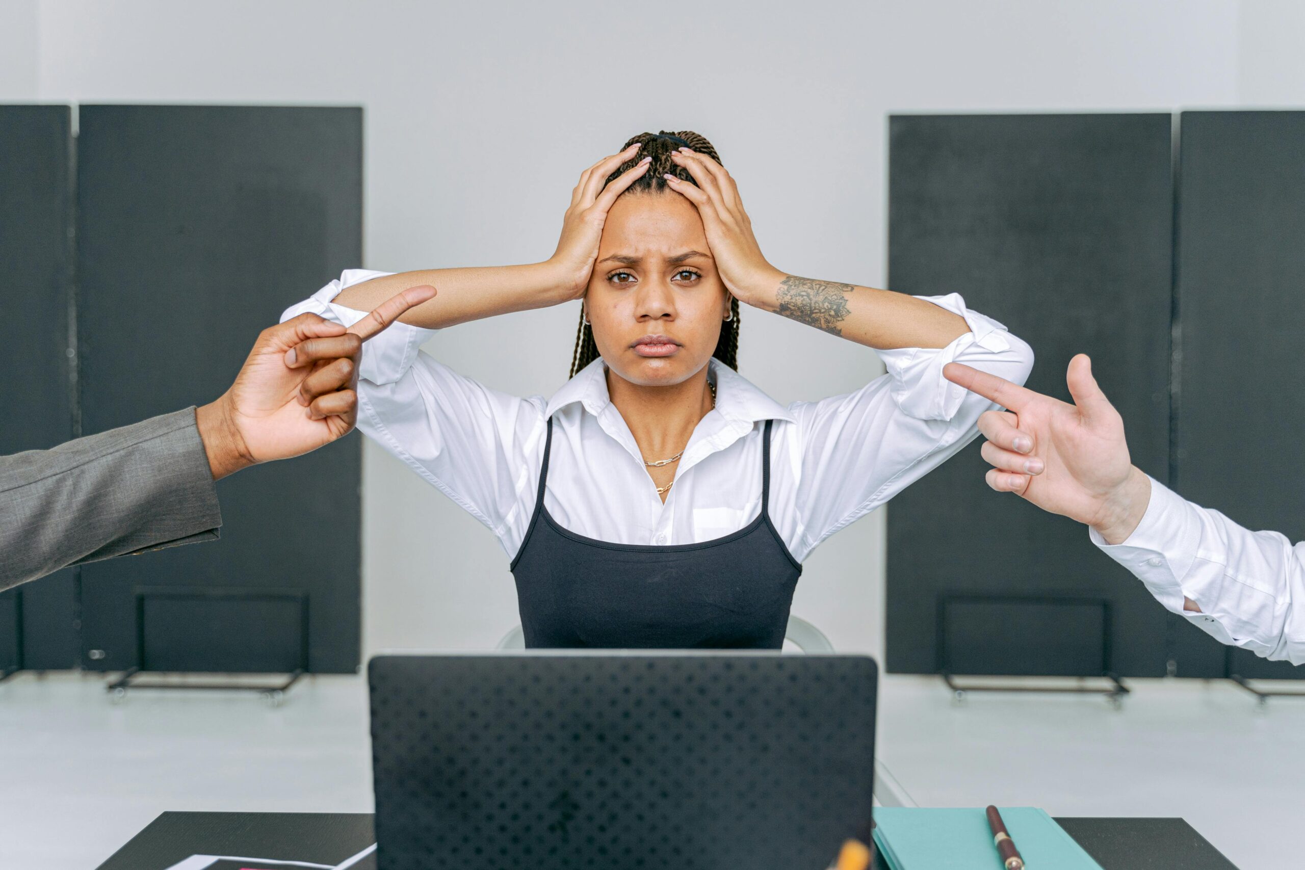 A stressed woman in an office setting receiving blame from coworkers, capturing workplace conflict.